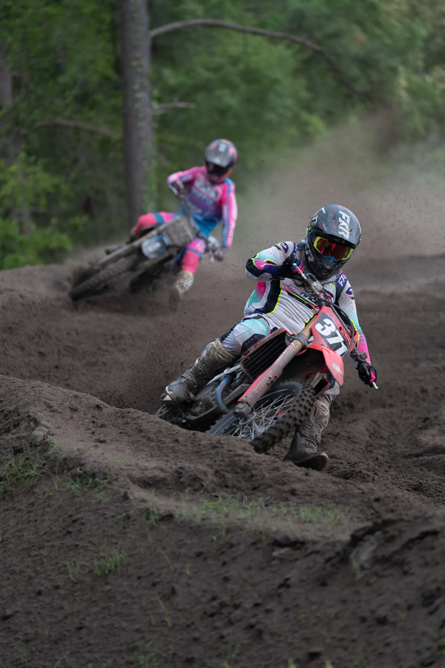 Two riders sweep through a dusty corner, the lead bike kicking up a cloud