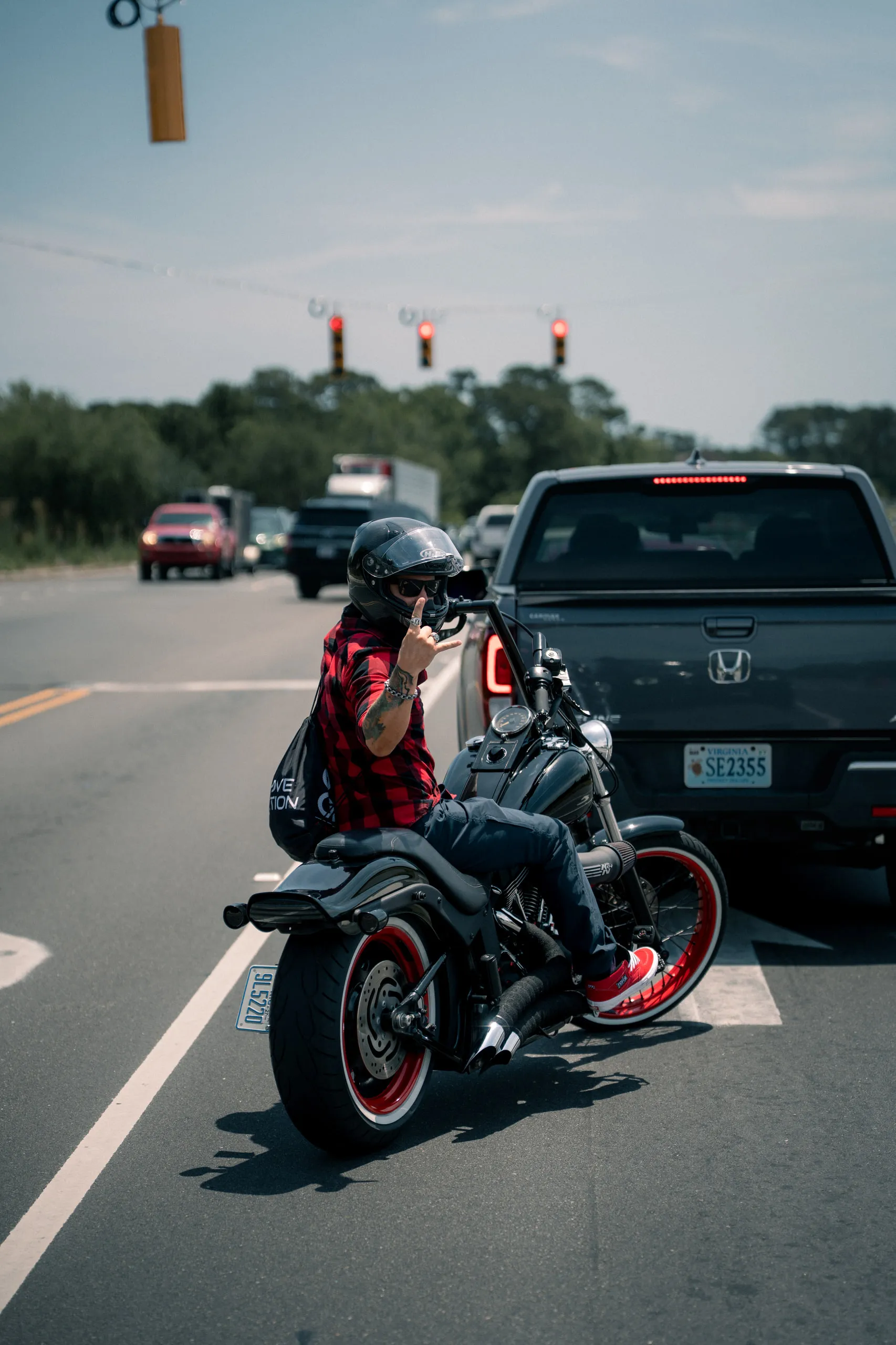 A rider in red plaid filters through stopped traffic at a light