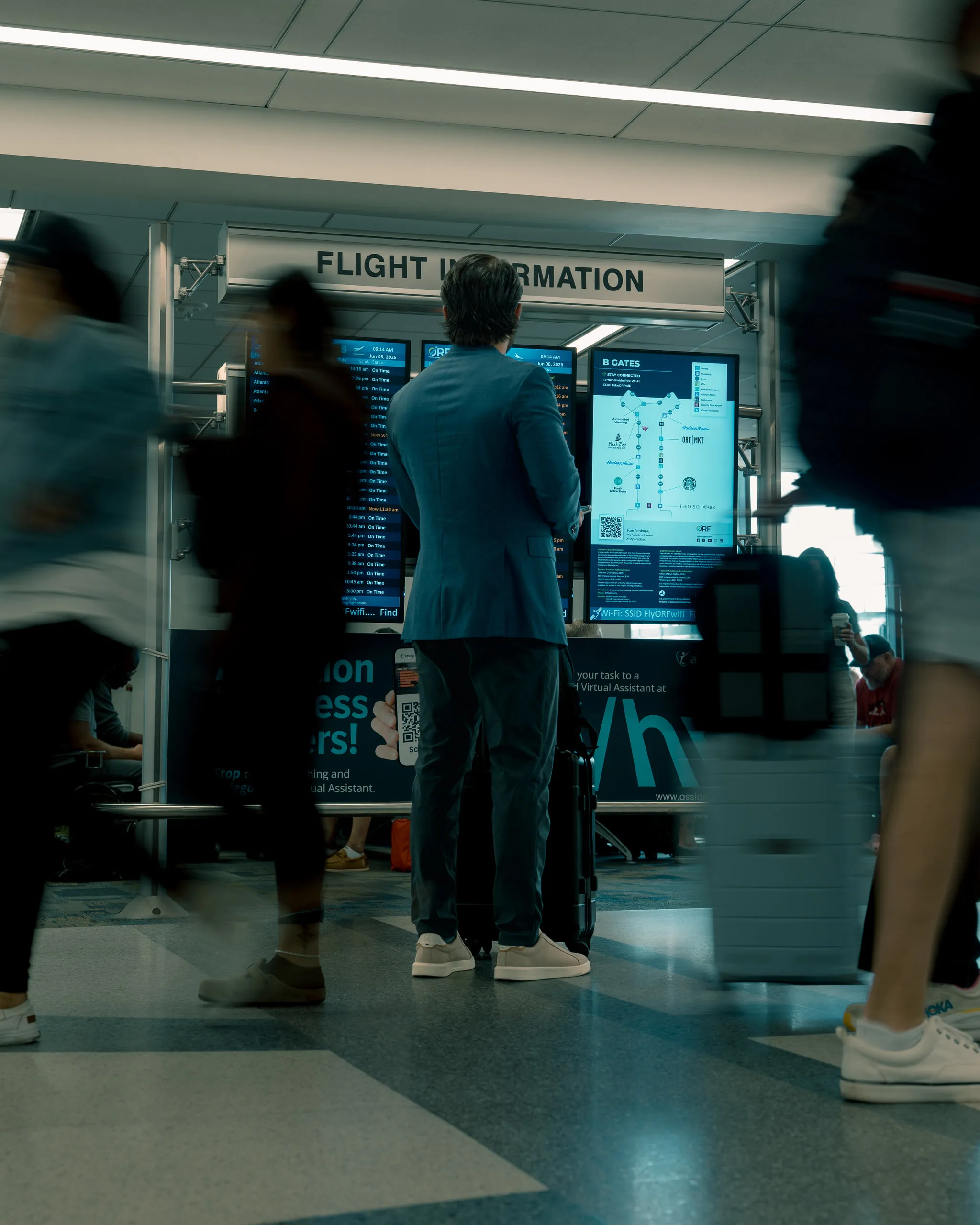 Travellers blur past a flight information board in an airport concourse